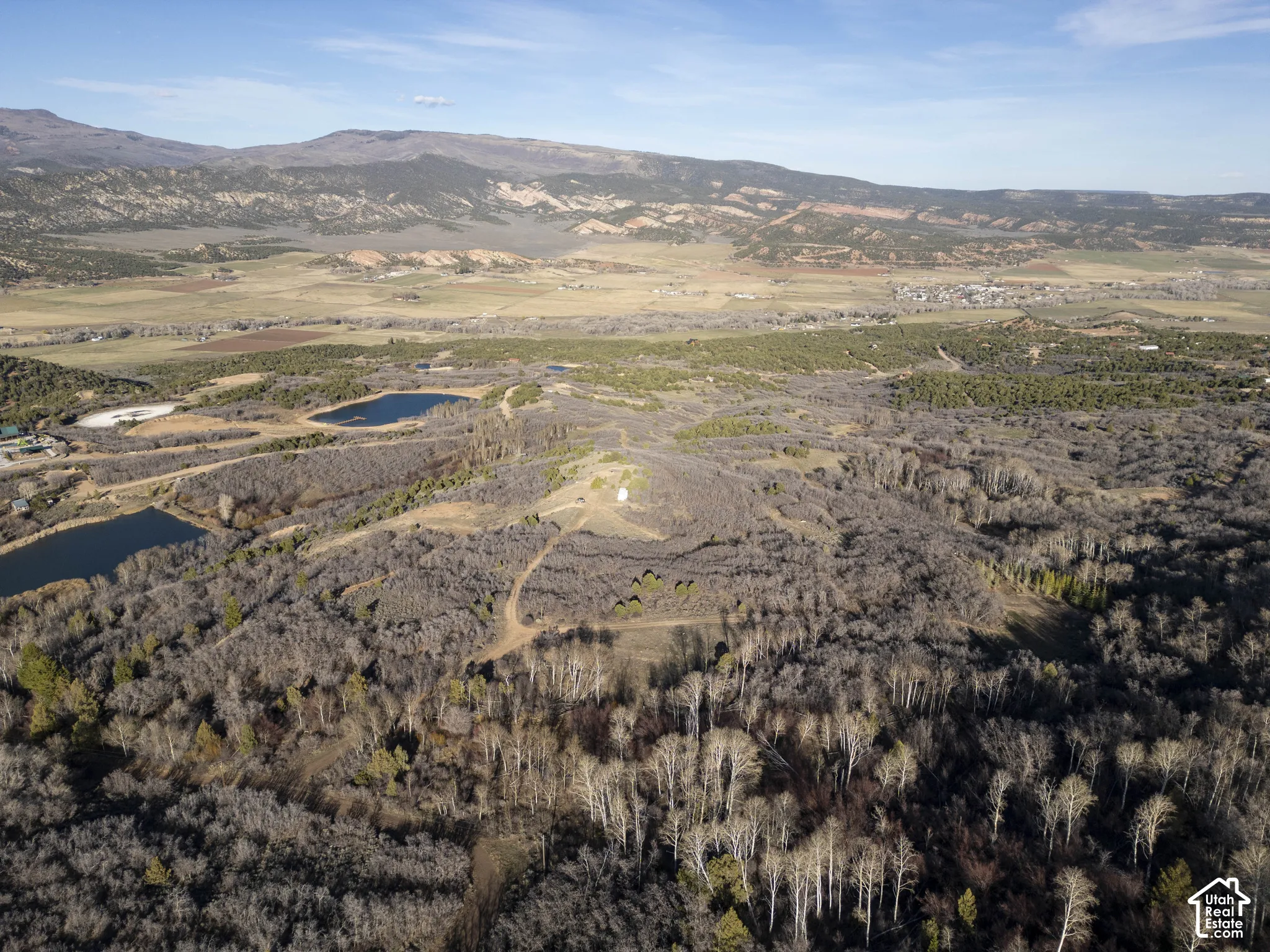 Mountainous terrain with natural bodies of water, extensive tree coverage, and an unpaved road