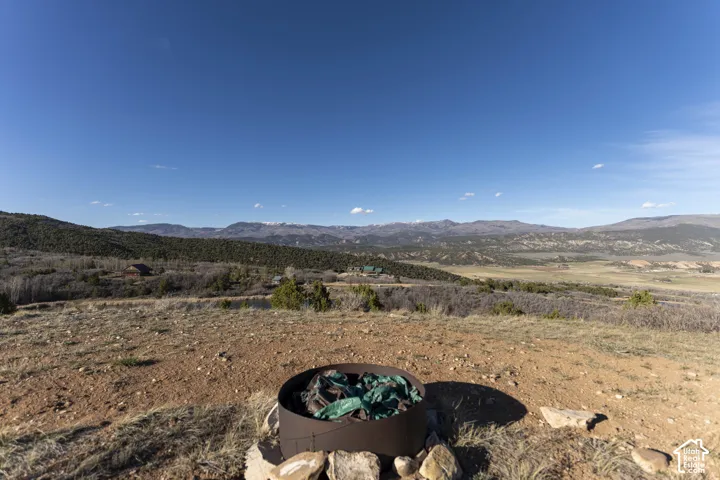 Expansive outdoor area featuring a metal fire pit, natural rock landscaping, and distant mountain ranges