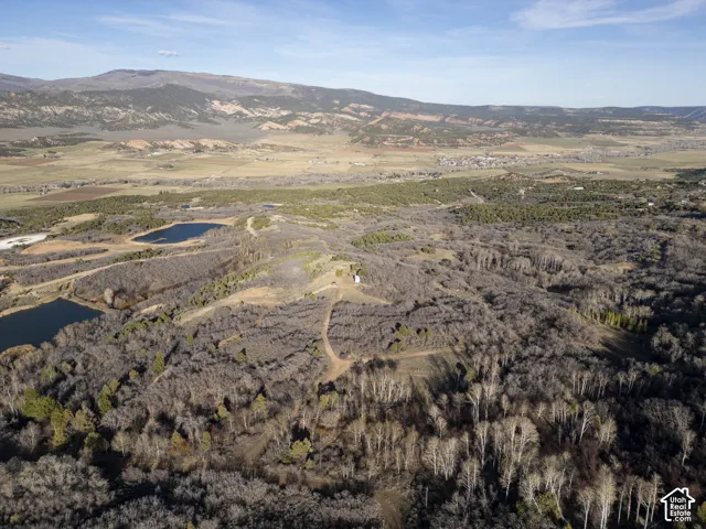 Expansive natural landscape with varied terrain, including distant mountains and a valley