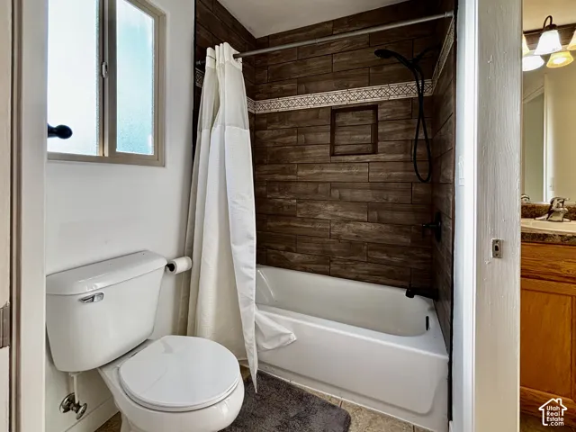 Bathtub with tile surround, black shower fixtures, decorative accent tile, and a recessed shower niche