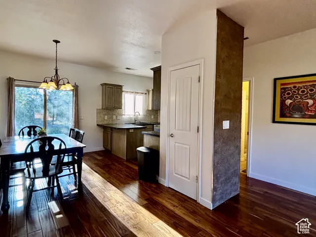 Wood flooring, sliding glass door, and a kitchen with wood-finish cabinetry and a tiled backsplash