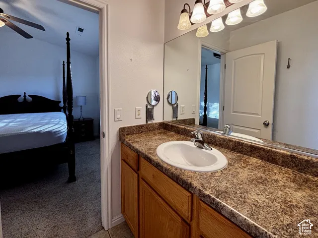 Vanity with a single basin, laminate countertop, wood-finish cabinetry, and an overhead light fixture