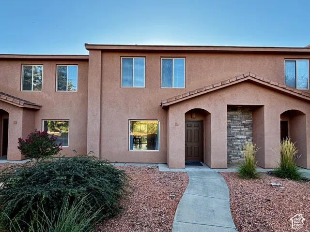 Stucco exterior with stone accent detailing, arched entryway, tile roof over the entry, and a paved walkway