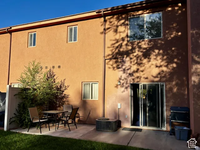 Private patio area with concrete slab, mature shrubbery, and sliding glass door access