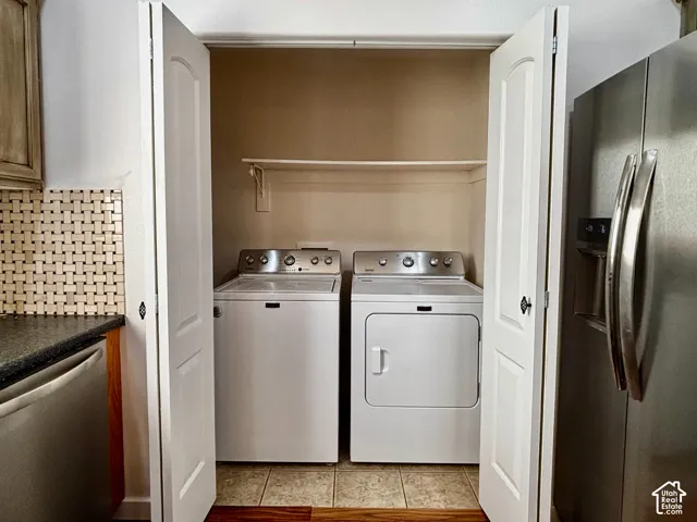 Laundry closet featuring bi-fold doors, a built-in shelf, and tile flooring