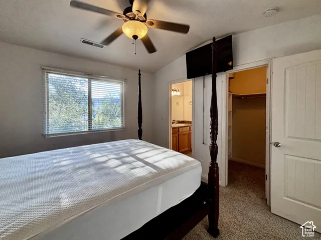 Carpeted room with a ceiling fan, a window with horizontal blinds, and a built-in closet with shelving