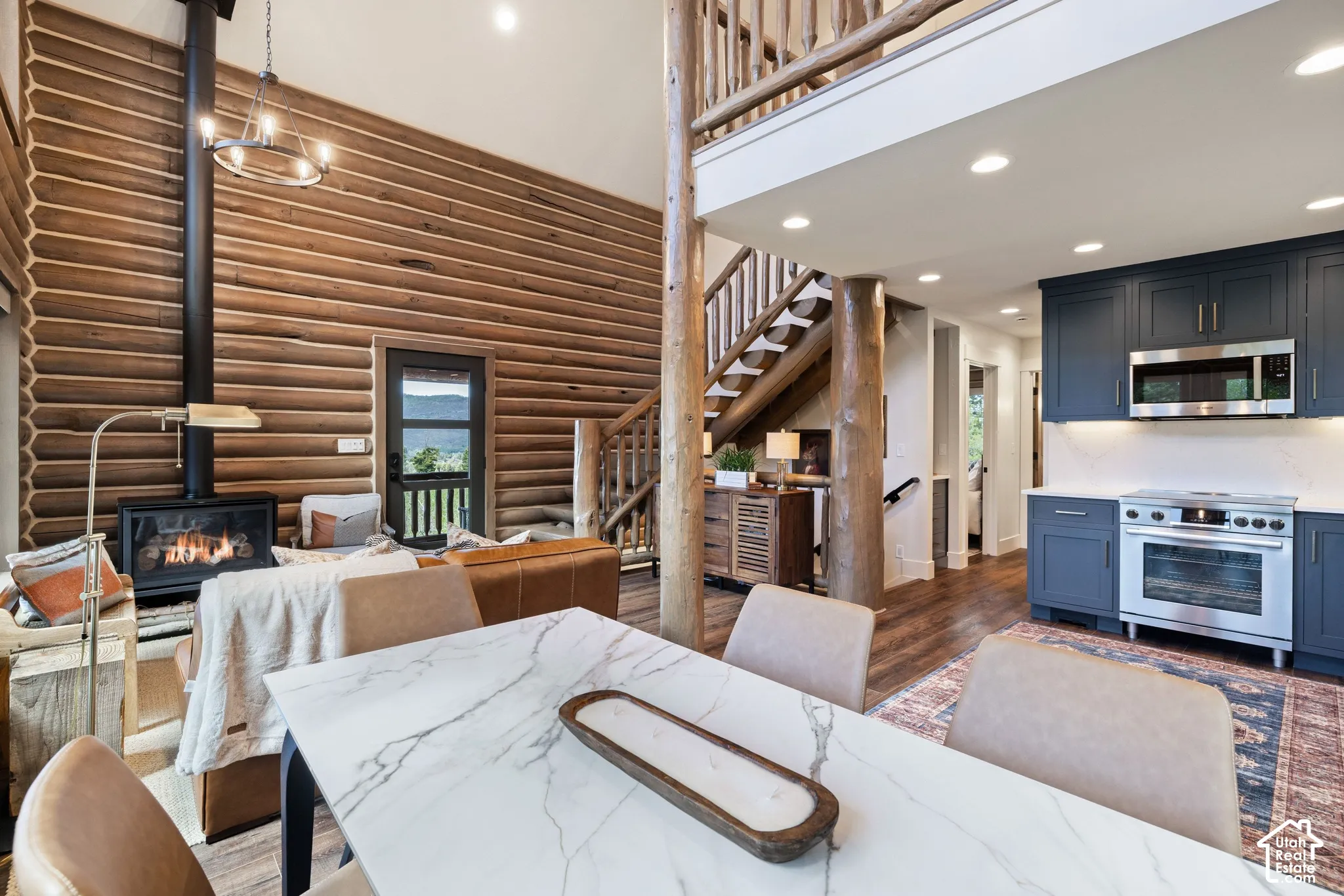 Open-concept living space with log walls, a built-in fireplace, and a white marble-patterned dining table