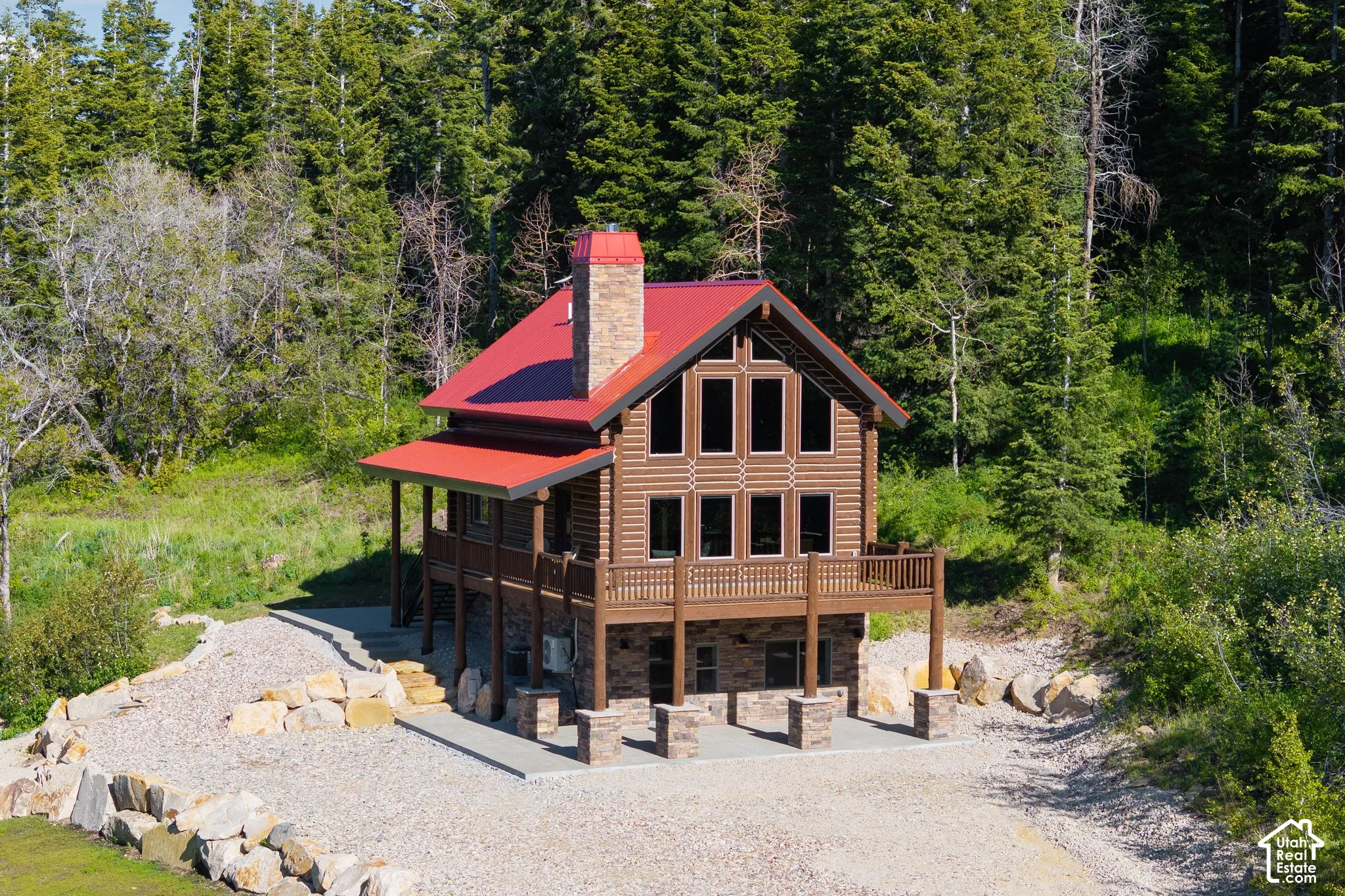 Log-style siding exterior with a red metal roof and a stone chimney