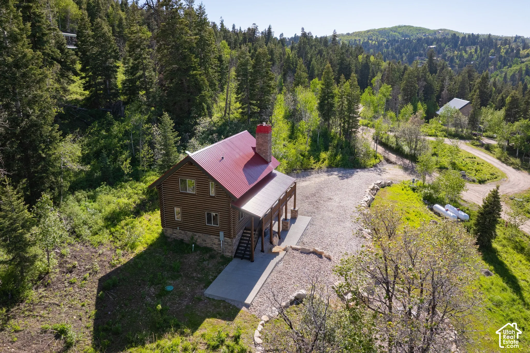 Log-sided residence with a red metal roof and stone foundation