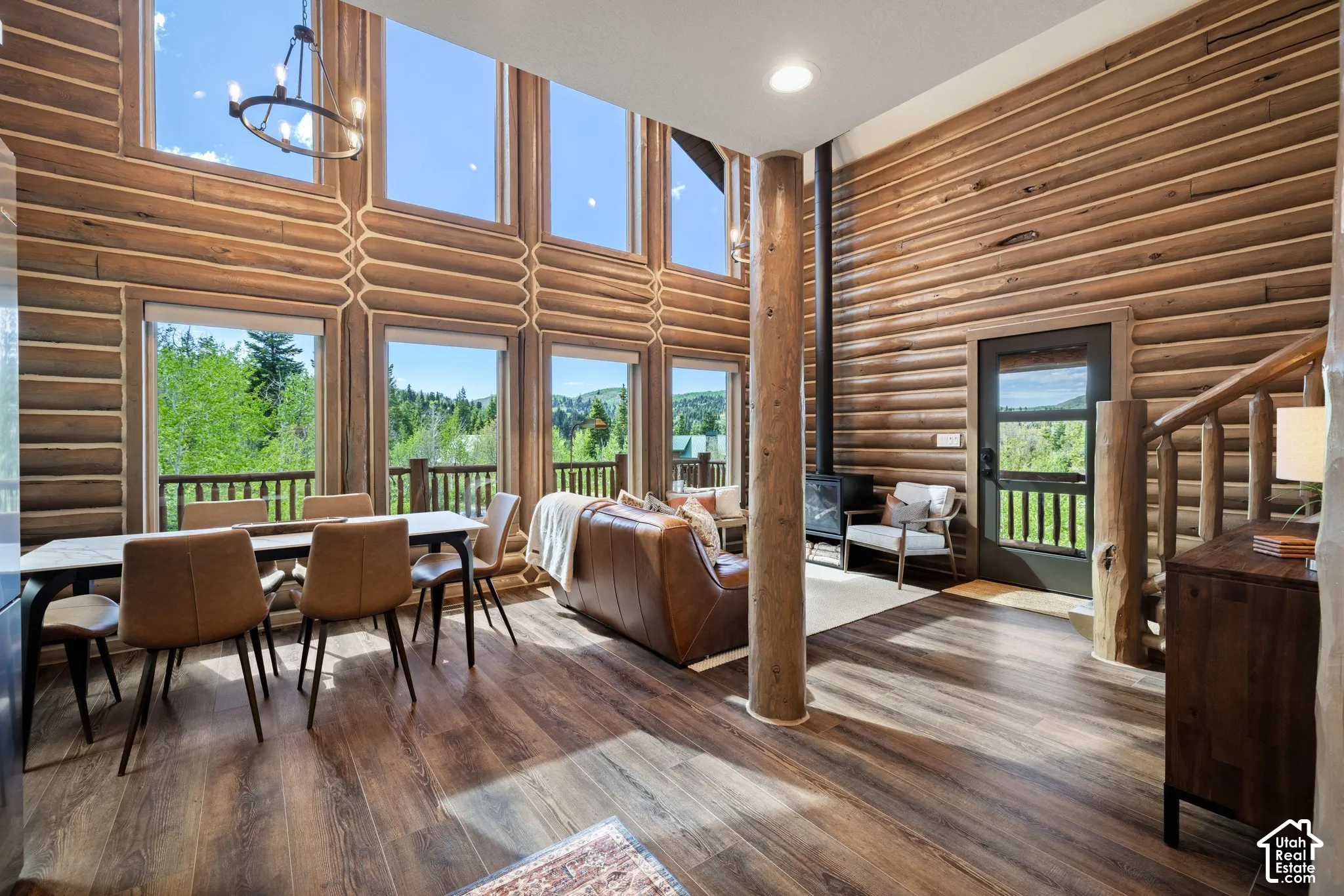 Vaulted ceiling with a chandelier, wood-finish flooring, wood-clad walls, and a freestanding wood-burning stove