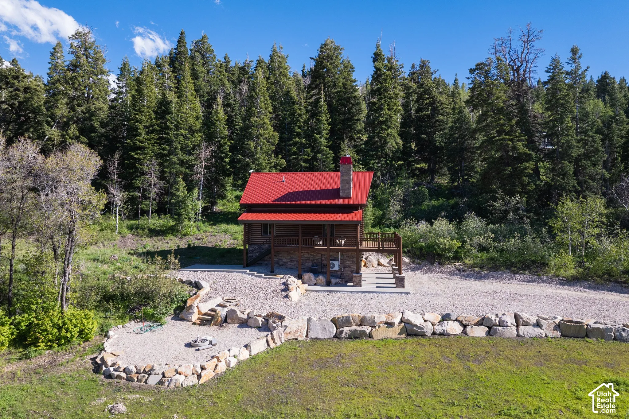Wood-sided cabin with a red metal roof and stone chimney