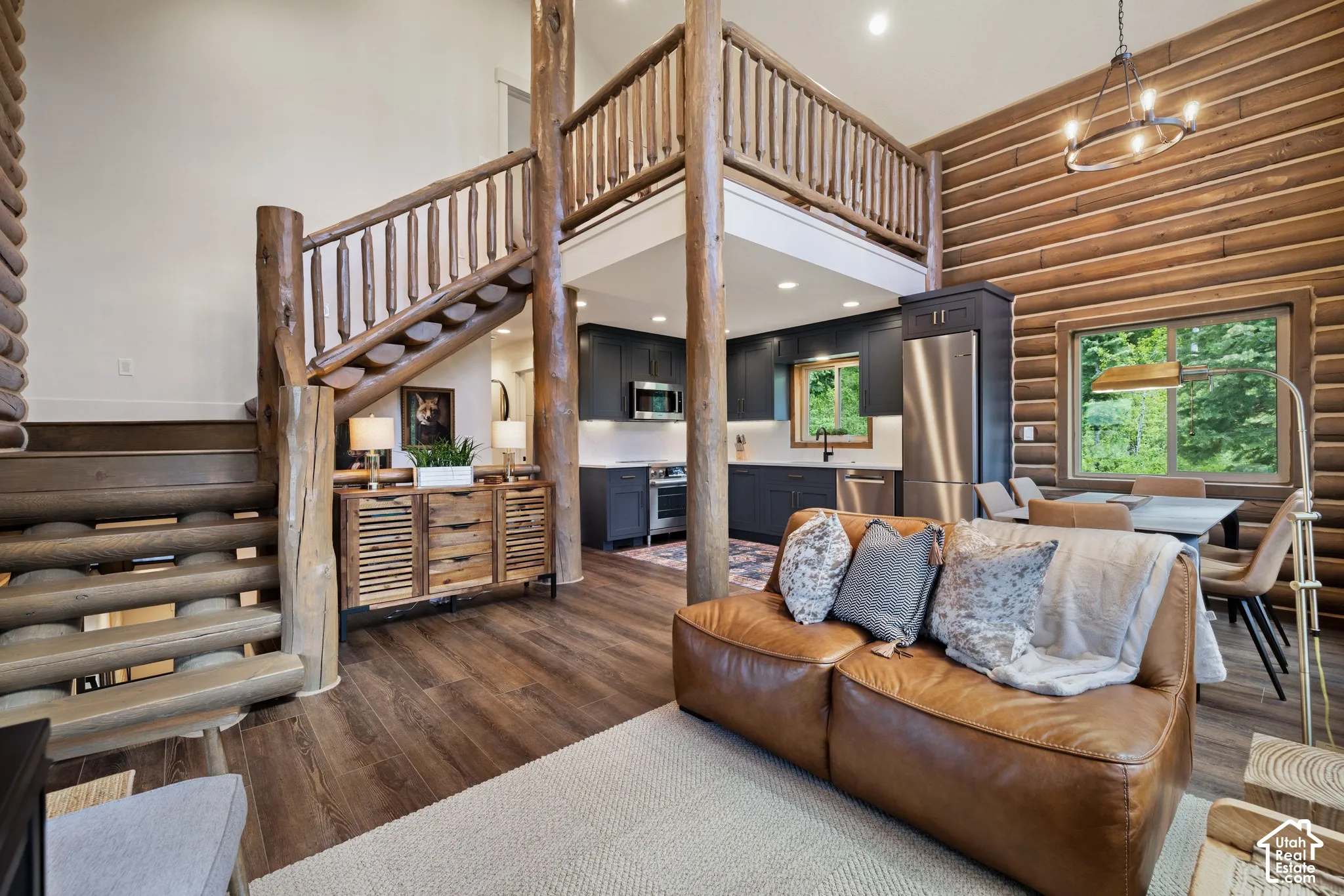Expansive interior featuring wood-finish flooring, log wall accents, and an open-concept kitchen with dark cabinetry