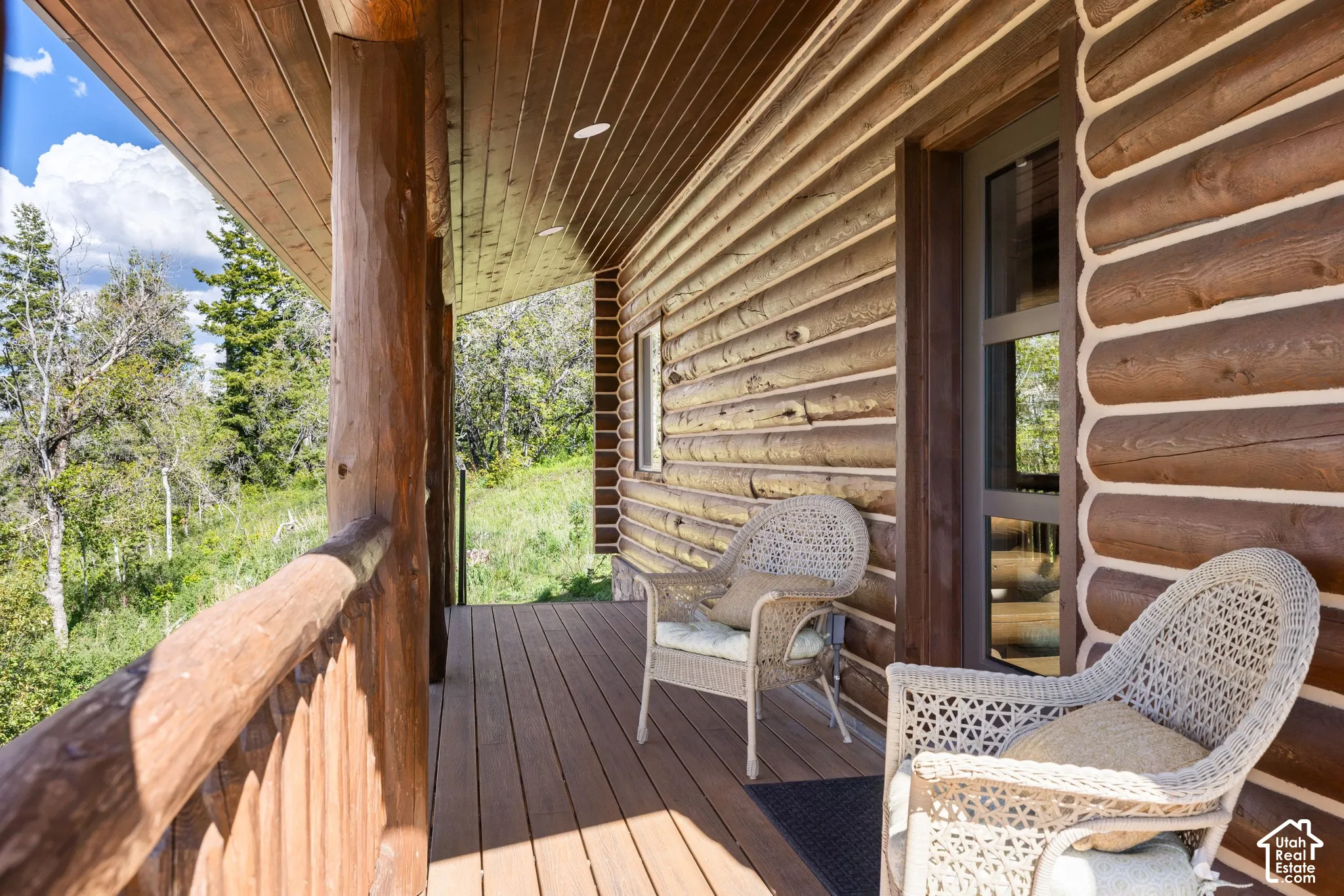 Wood-paneled ceiling, log cabin exterior, wood railing, wood-finish flooring, and glass-paneled door