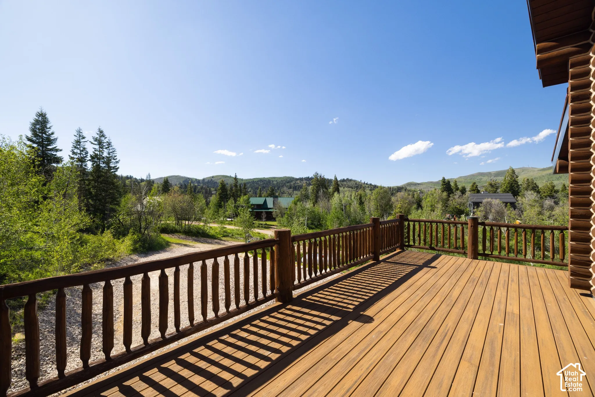 Expansive wooden deck with turned balusters, featuring a wood plank surface and a log-style exterior wall