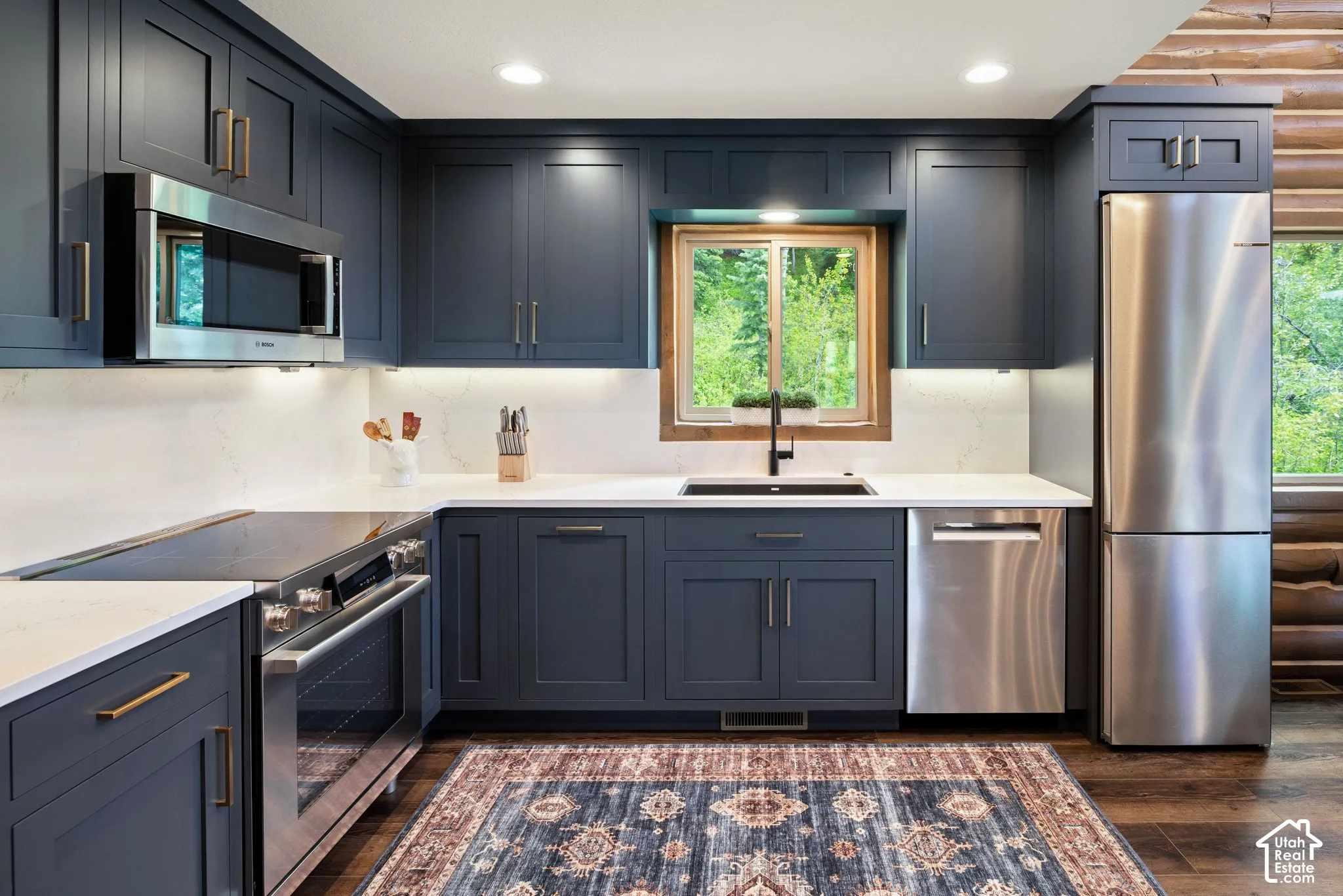 Kitchen featuring dark blue cabinetry, white countertops, stainless steel appliances, and wood-finish flooring