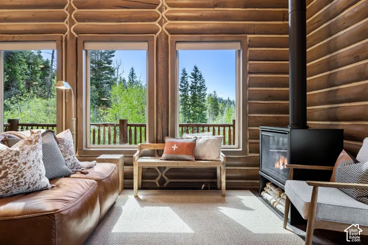 Expansive log wall construction, multiple large picture windows, and a built-in fireplace with a hearth