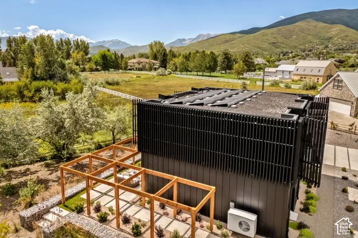 Modern exterior with dark vertical siding, rooftop solar panels, and a wood pergola
