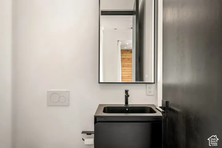 Wall-mounted vanity with integrated sink, matte black faucet, and an illuminated mirror