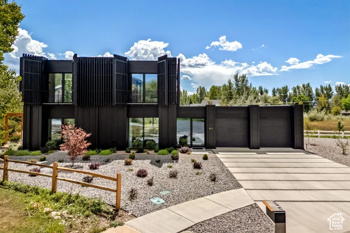 Contemporary black exterior with large windows, two-car garage, and an expansive concrete driveway