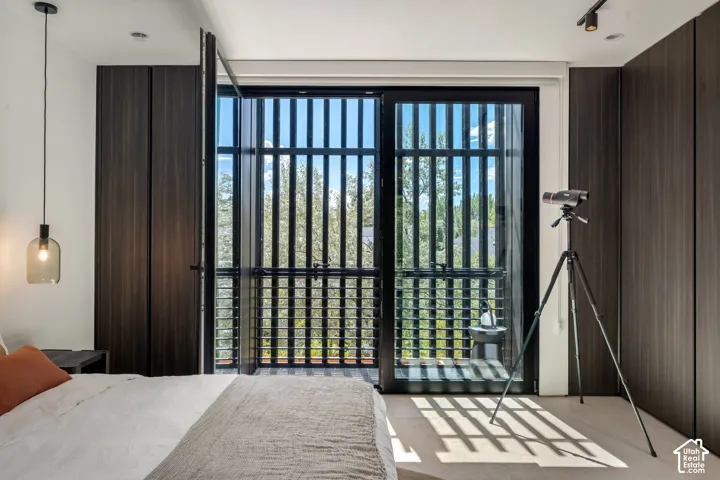 Full-height sliding glass doors opening to a balcony, integrated dark wood-finish cabinetry, recessed ceiling lights, and contemporary pendant lighting