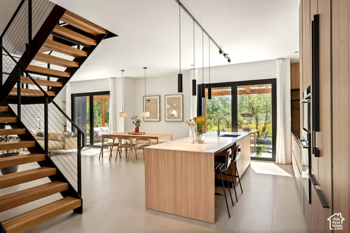 Open-concept living space with a wood staircase featuring black metal railings and cable infill