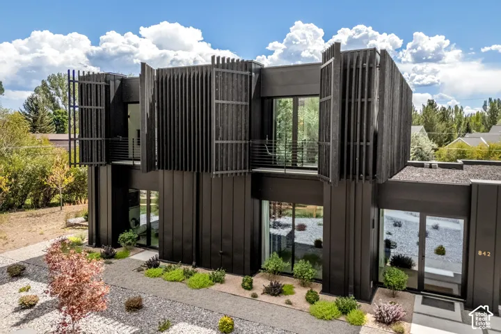 Modern architectural design featuring dark vertical siding and multiple floor-to-ceiling windows
