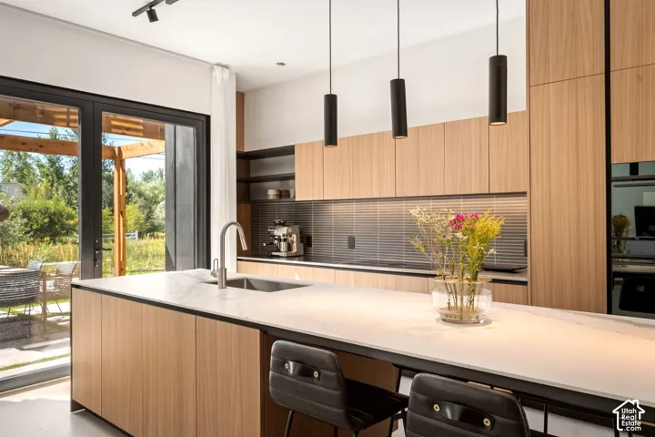 Sleek kitchen with wood-finish cabinetry, a large center island with a built-in sink, and a light-toned countertop
