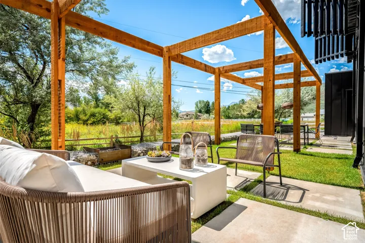Expansive outdoor living area featuring a wooden pergola, concrete patio, and lush green lawn