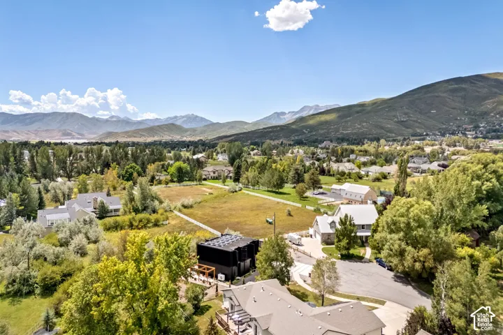 Expansive surrounding landscape featuring mountainous terrain, mature trees, and a distant body of water