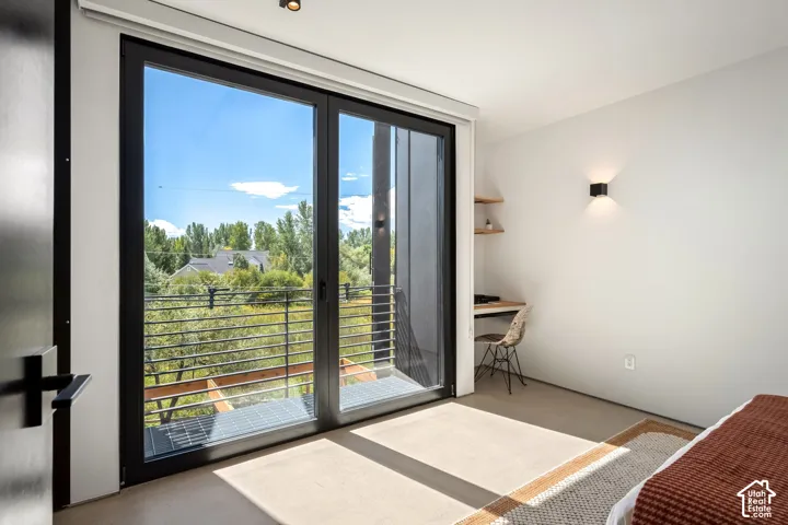 Sliding glass doors with a balcony, built-in corner desk, and wall-mounted sconce lighting