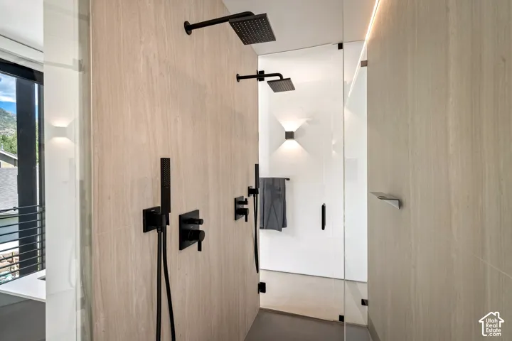 Dual rain shower heads with matte black fixtures, stone-look tile walls, and a glass-enclosed shower