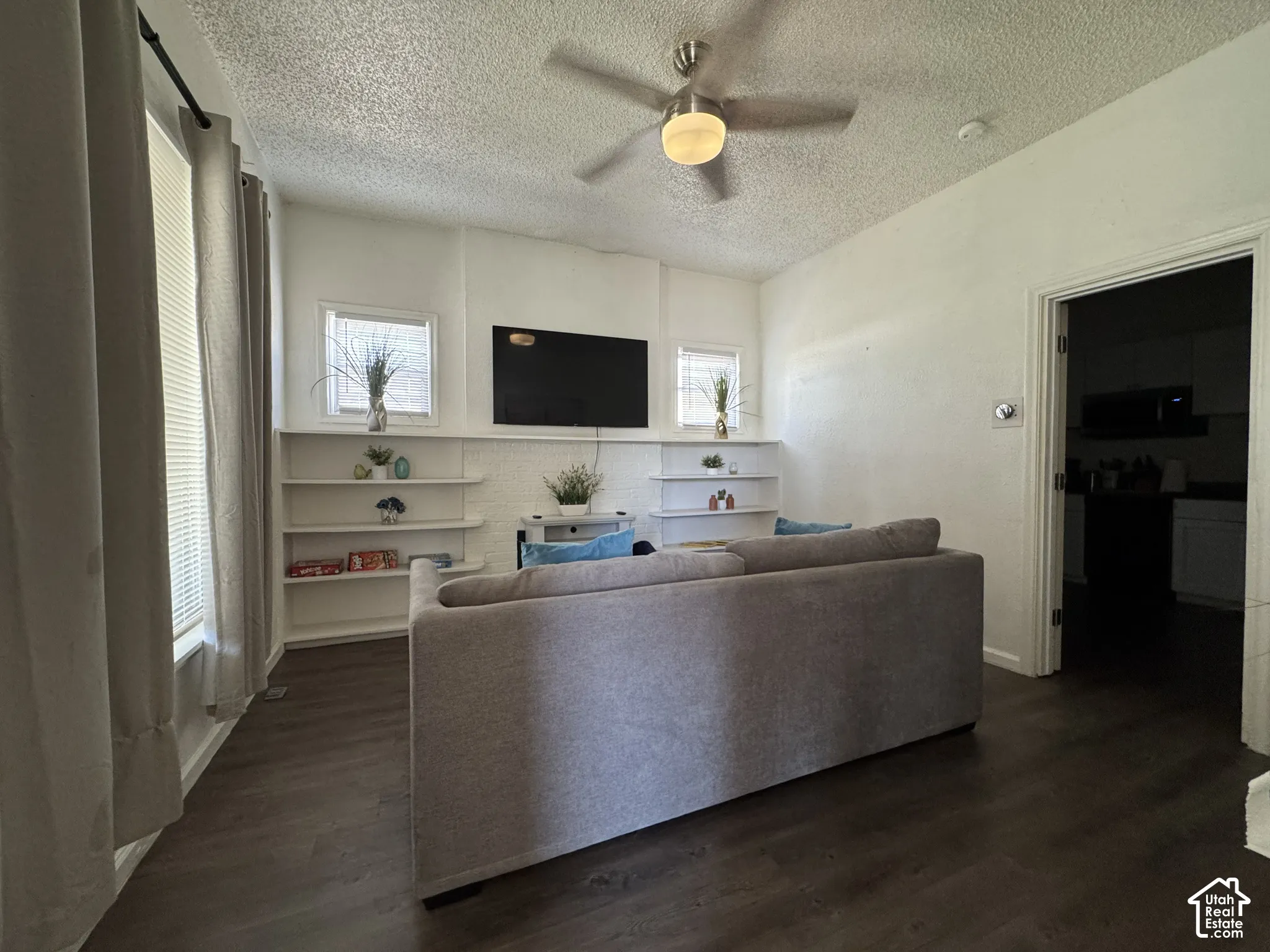 Recessed built-in shelving, wood-finish flooring, and a ceiling fan with integrated lighting