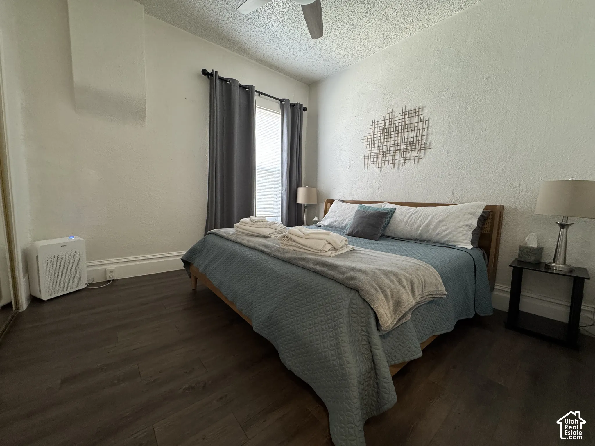 Dark wood-finish flooring, ceiling fan, window with curtain rod, and baseboard trim