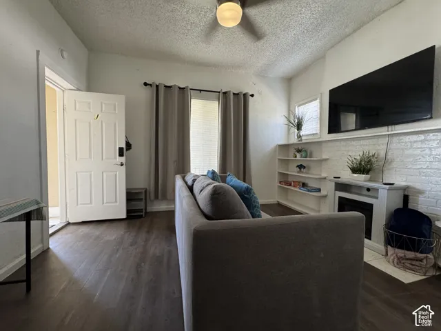 Vaulted ceiling with an attached light fixture, wood-finish flooring, and a white brick-finish accent wall