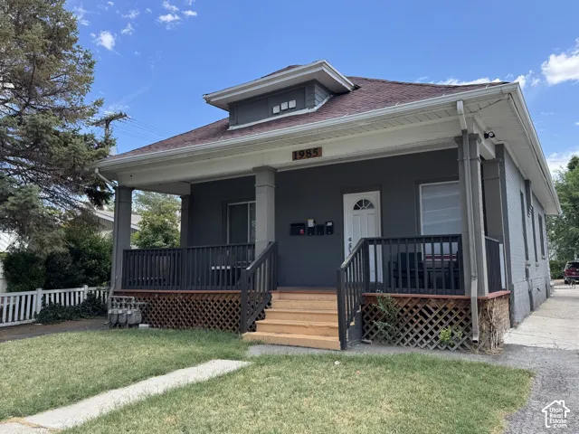 Front porch with wood railing and columns, featuring a wood lattice foundation skirt