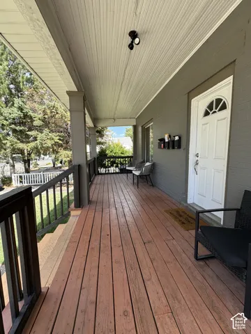Expansive covered porch featuring wood-finish decking, painted wood railings, and decorative support columns