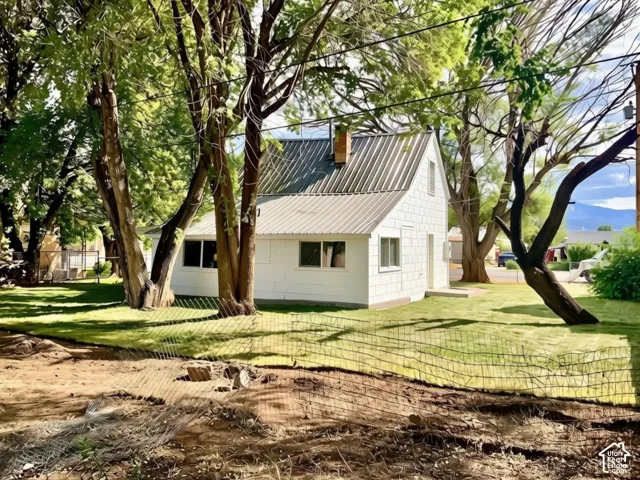 White exterior siding, metal roof, and a chimney feature