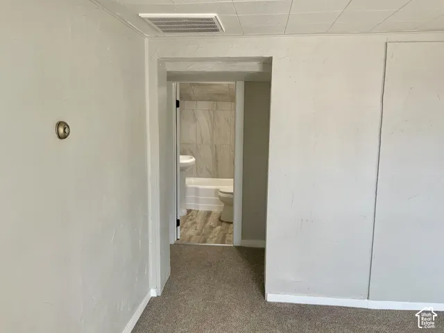 Carpeted flooring, white textured walls, and a recessed ceiling panel
