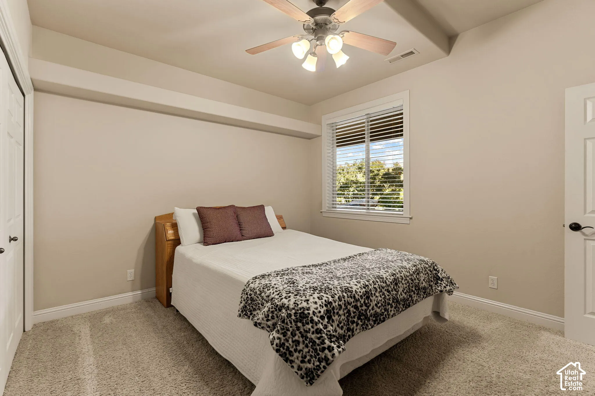 Carpeted room featuring a window with blinds, a ceiling fan with integrated lighting, and a paneled door
