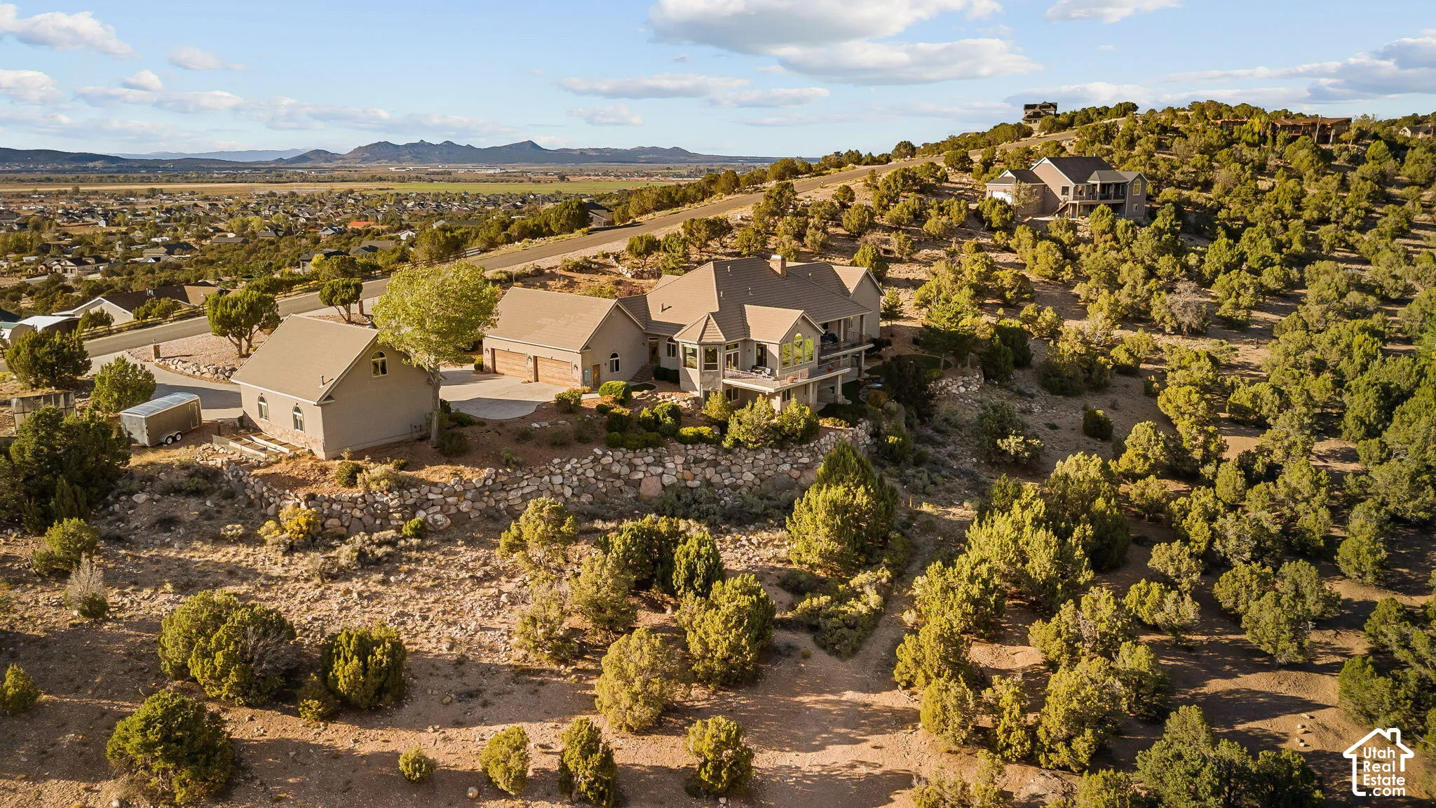 Expansive property set on a natural hillside with mature trees, featuring a multi-level residence with a walk-out lower level, an attached garage, and a detached auxiliary building