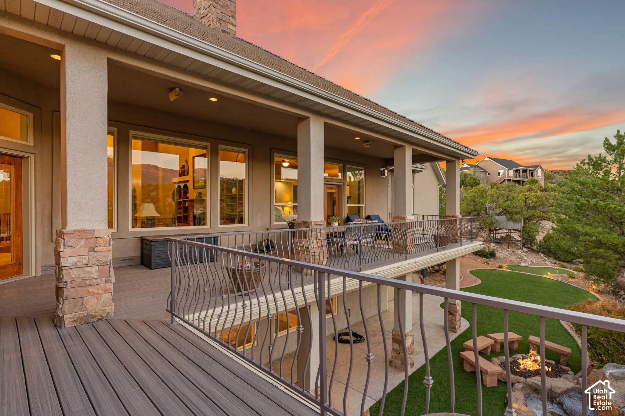 Expansive elevated deck with composite decking, stone-clad columns, and wrought iron railing