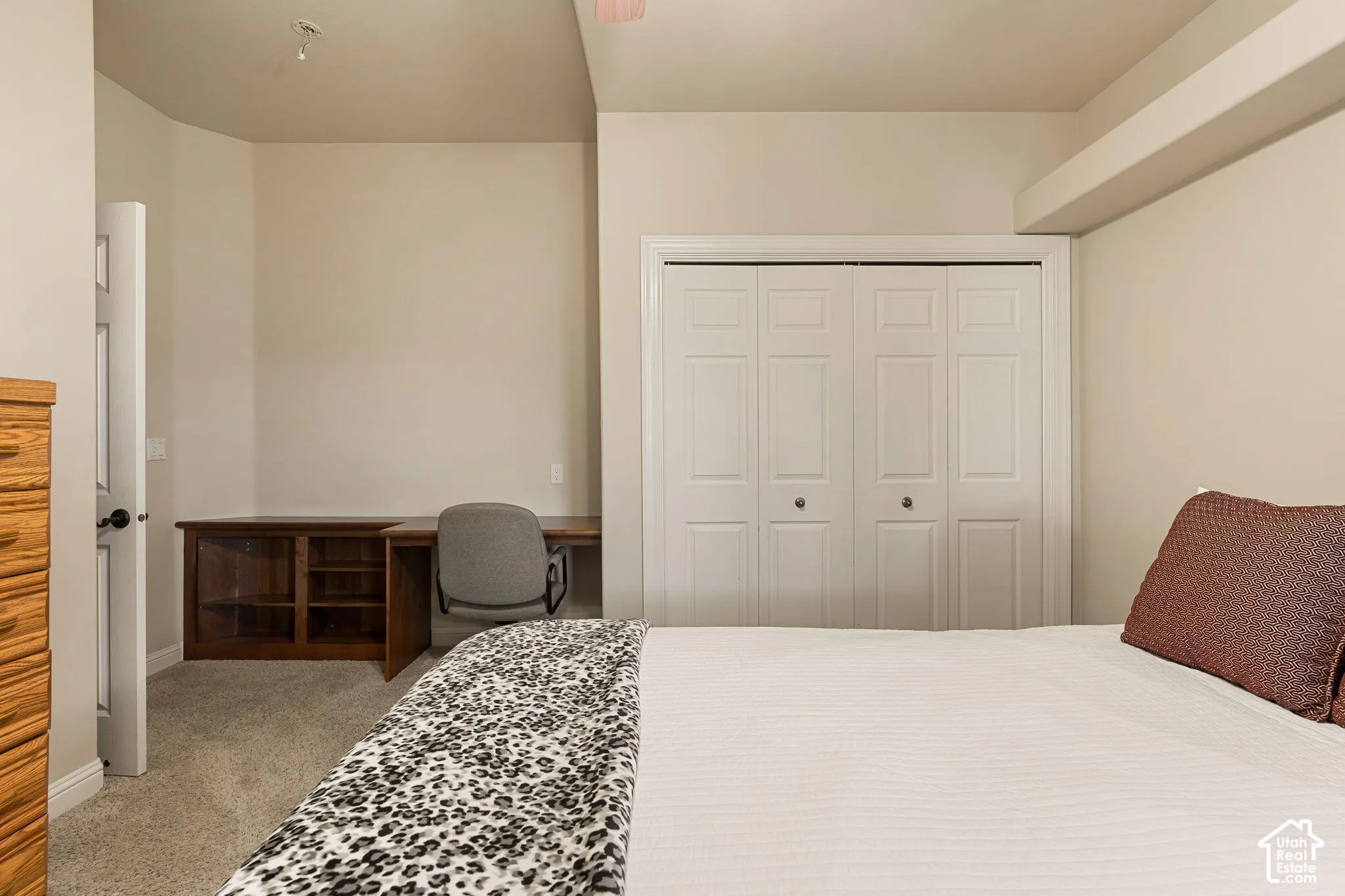 Built-in desk with wood-finish cabinetry, neutral carpeting, and bi-fold closet doors