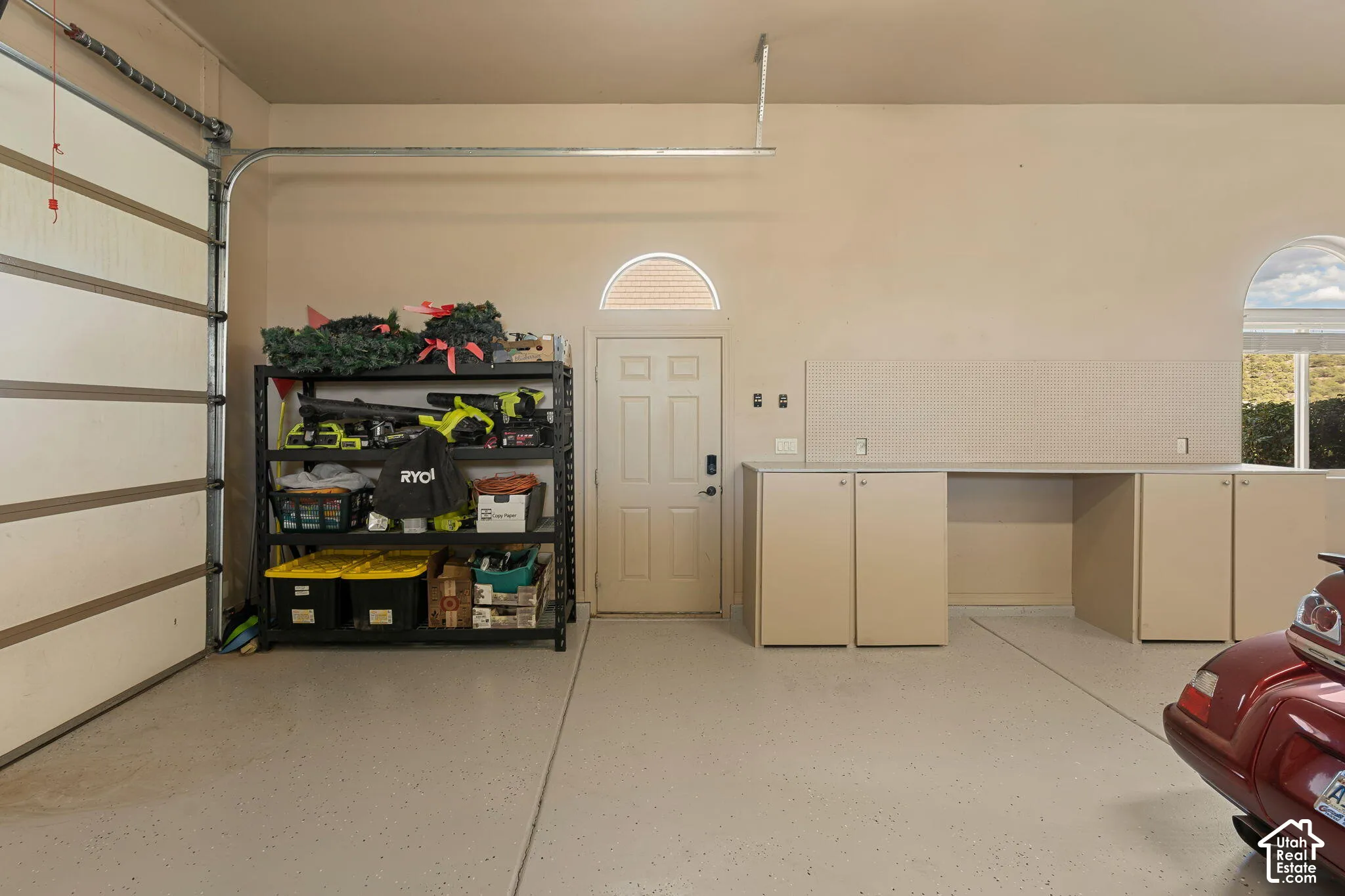 Garage with epoxy flooring, built-in cabinetry, arched windows, and a side access door