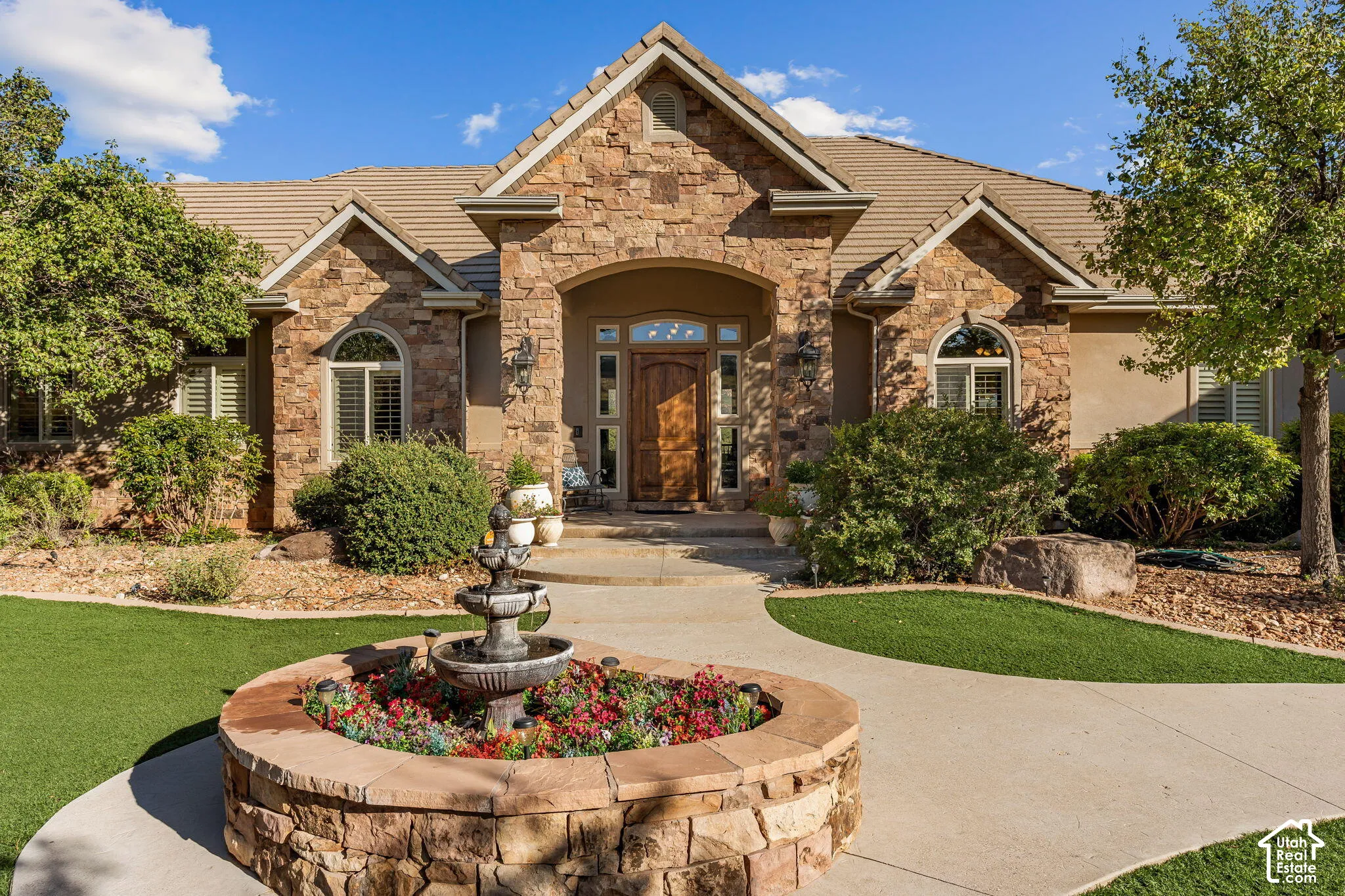 Stone veneer exterior with arched entry, wood-finish front door, arched windows, and tile roof