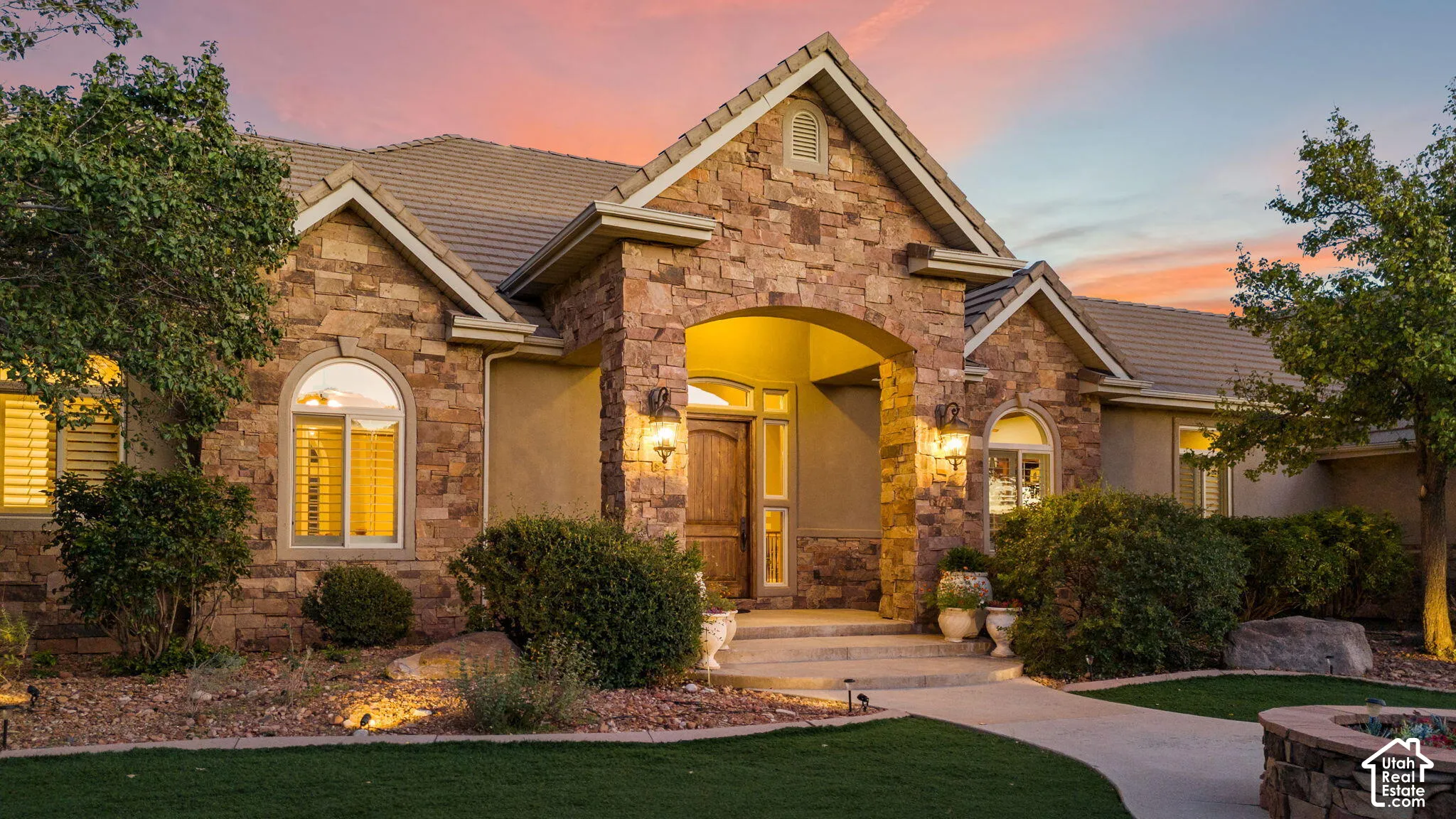 Stone facade with arched entryway, a tile roof, and exterior wall sconces