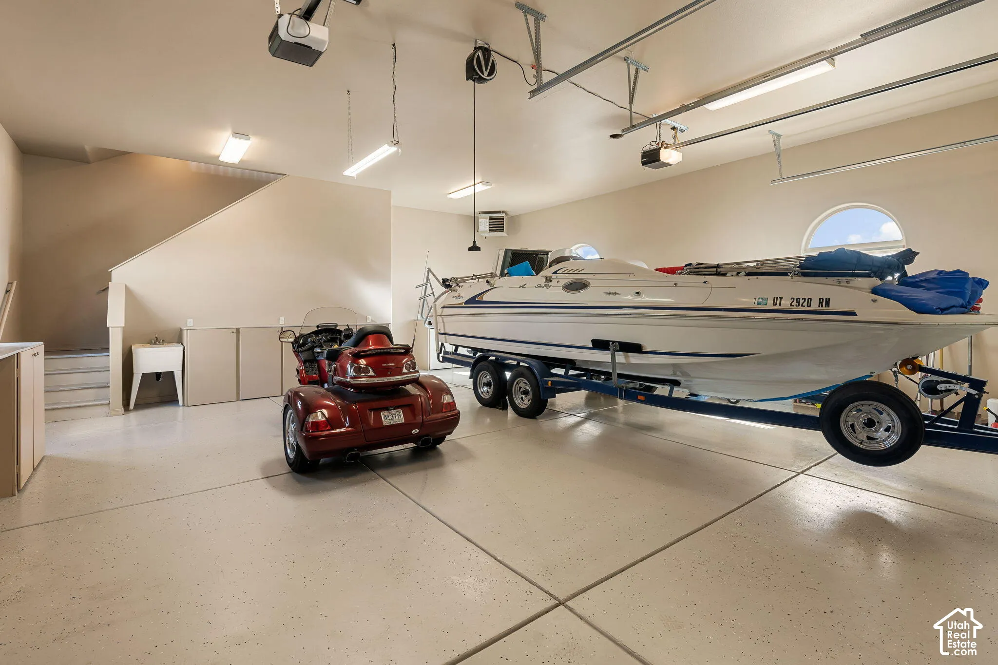 Expansive garage with epoxy flooring, built-in cabinetry, utility sink, and overhead lighting