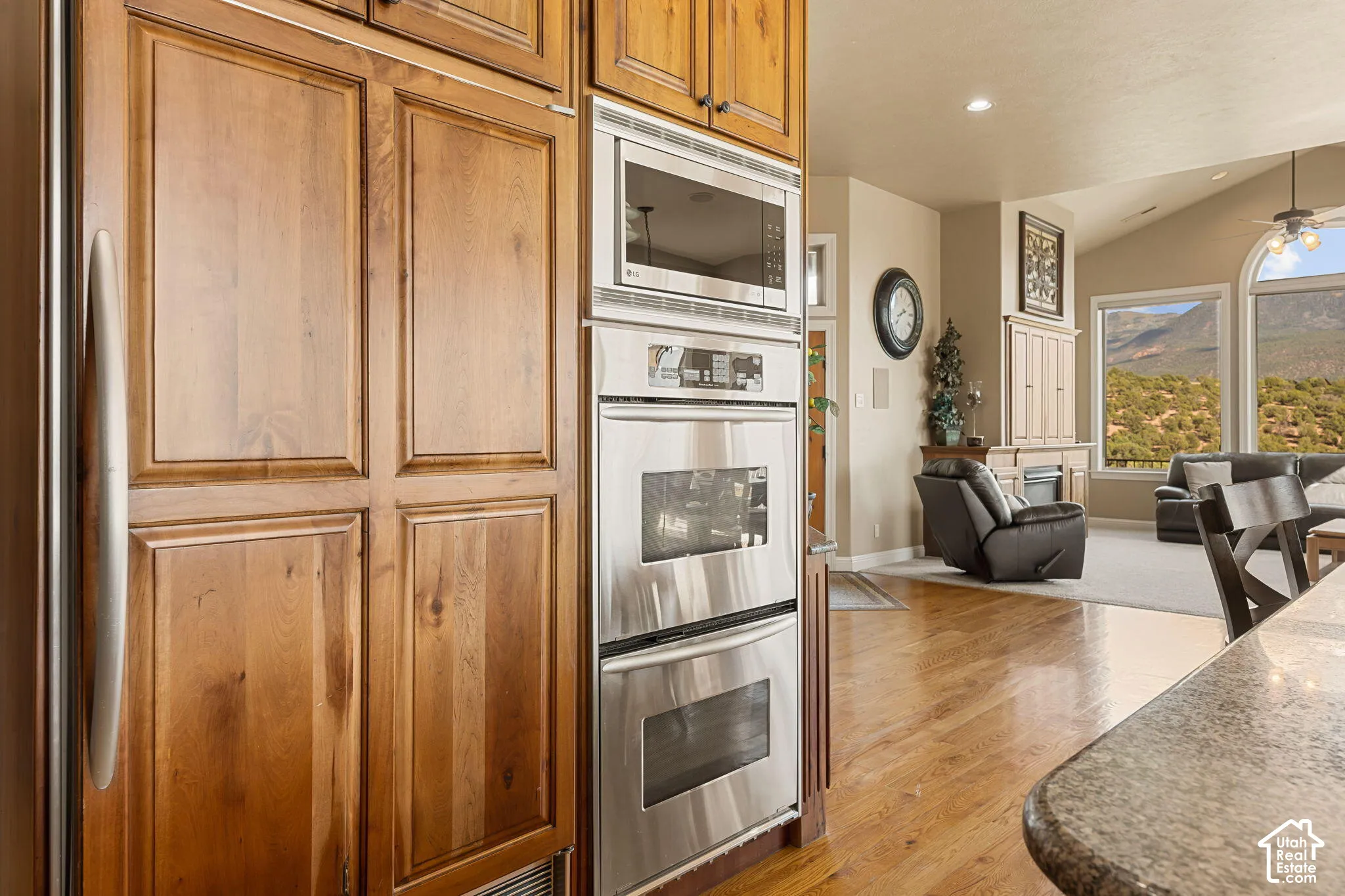 Built-in stainless steel appliances, wood-finish flooring, vaulted ceiling, large windows, and a built-in entertainment center