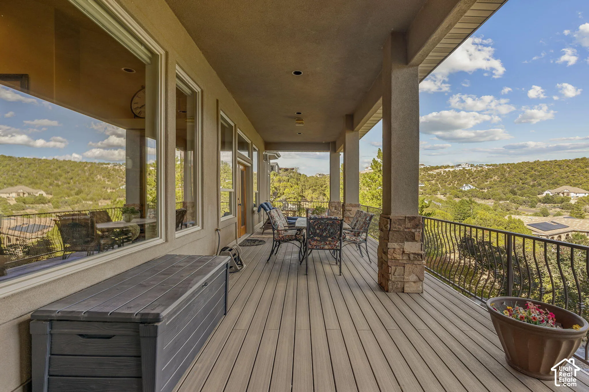 Expansive covered deck featuring composite decking, decorative metal railings, and stone-clad columns