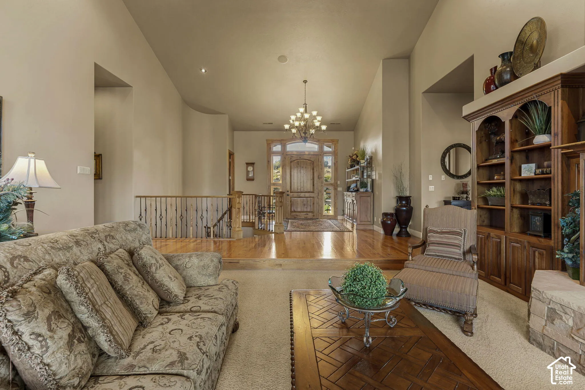 Vaulted ceilings, built-in shelving, wood-finish flooring, staircase with decorative railing, and recessed lighting