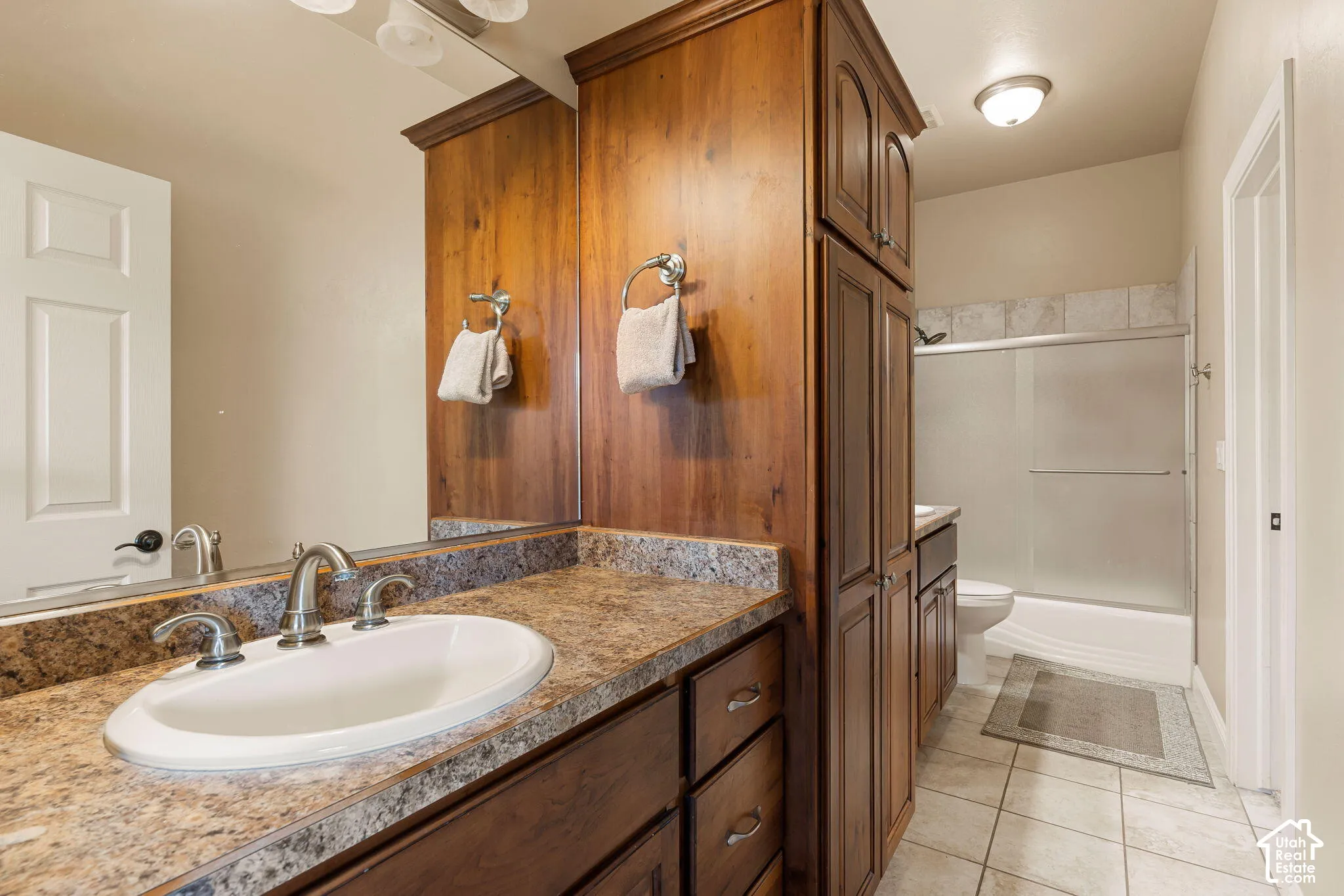 Vanity with an integrated oval sink, brushed nickel faucet, and a granite-finish countertop